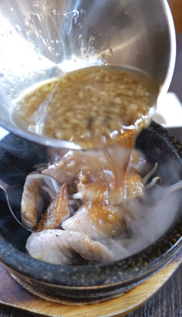 豪気 南鴨宮店の豚トロにタレをかける様子